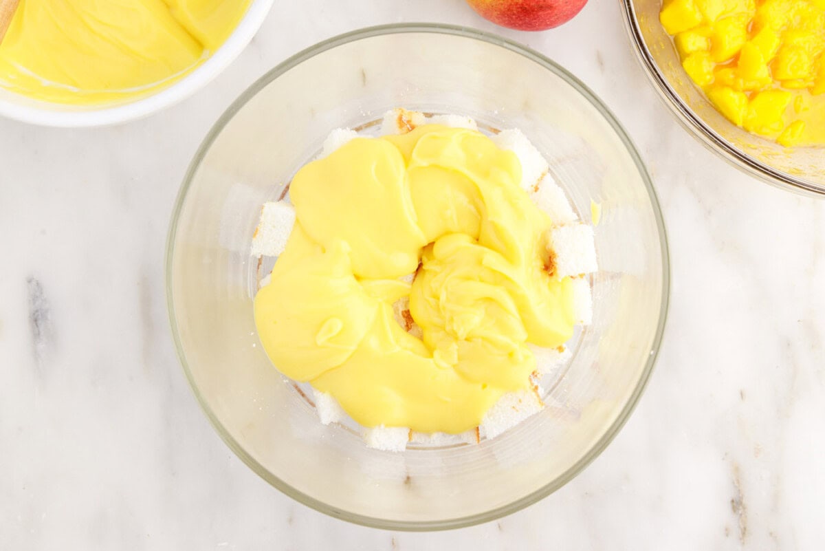 vanilla pudding on top of angel food cake in a trifle dish