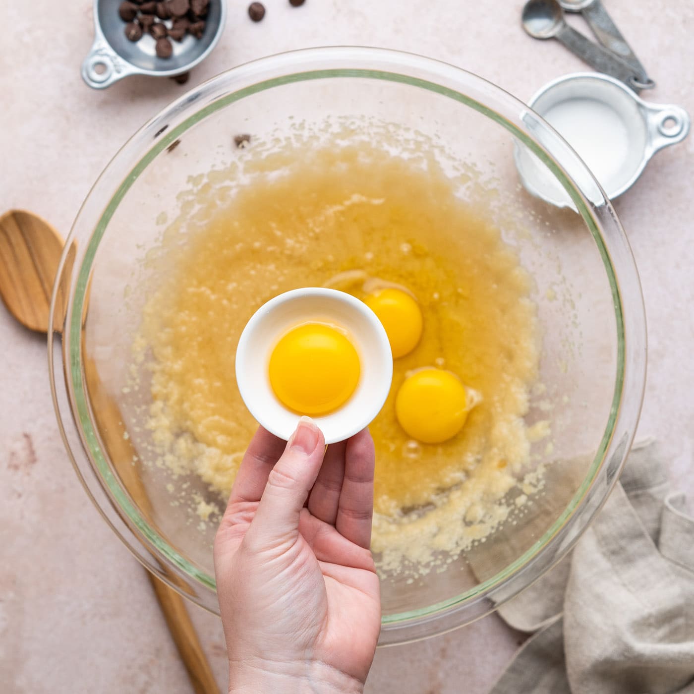 adding egg yolk to brownie batter in a bowl
