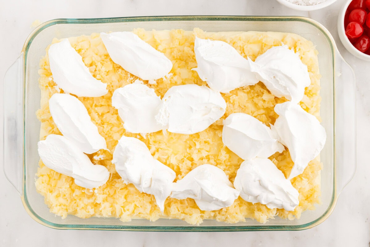 dollops of cool whip over crushed pineapple on cake