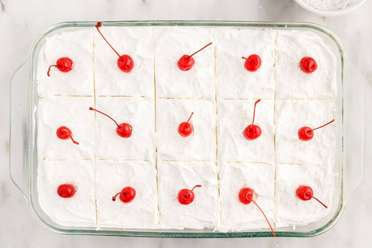 millionaire's cake sliced with maraschino cherries and shredded coconut
