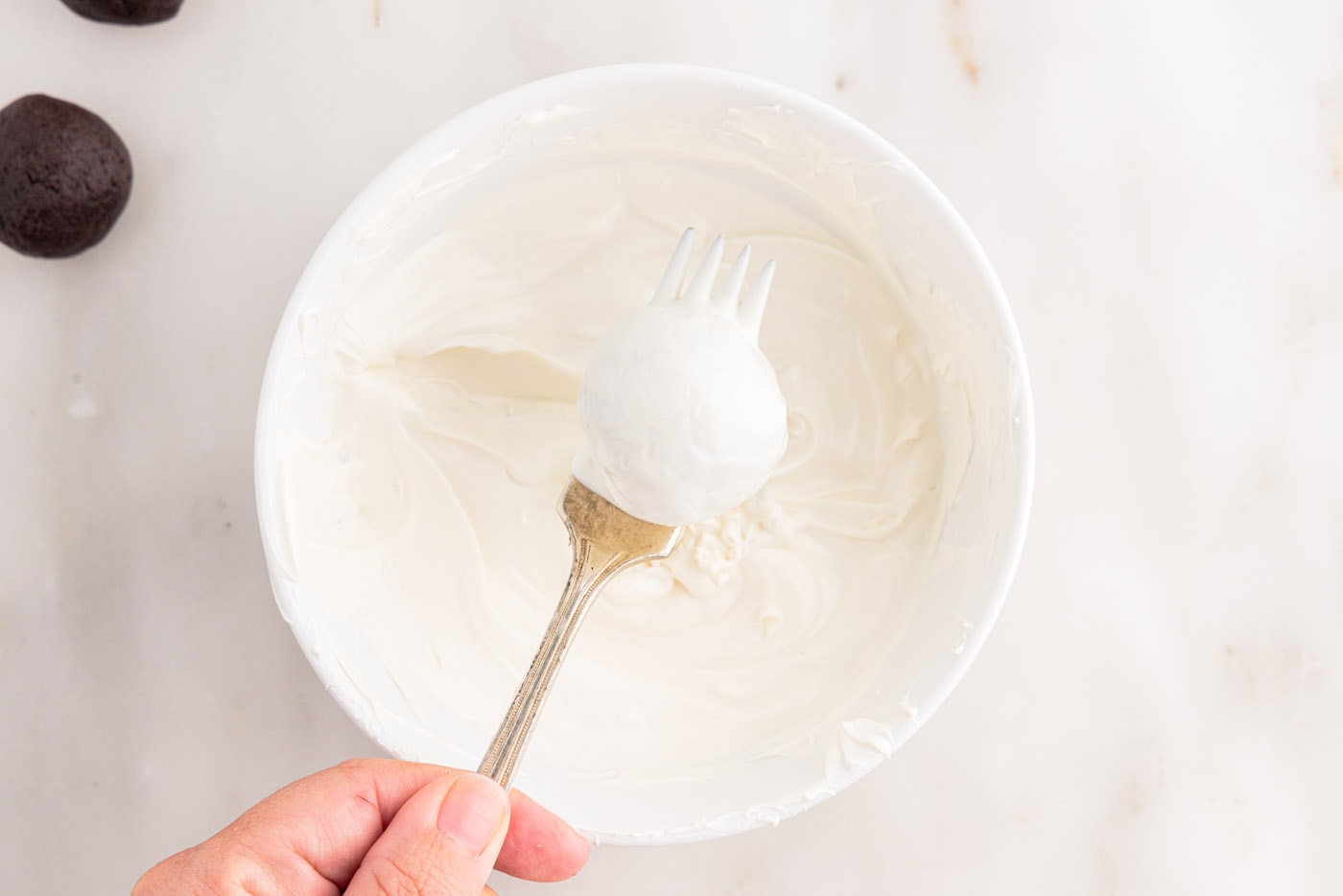 removing oreo truffle from white chocolate with a fork