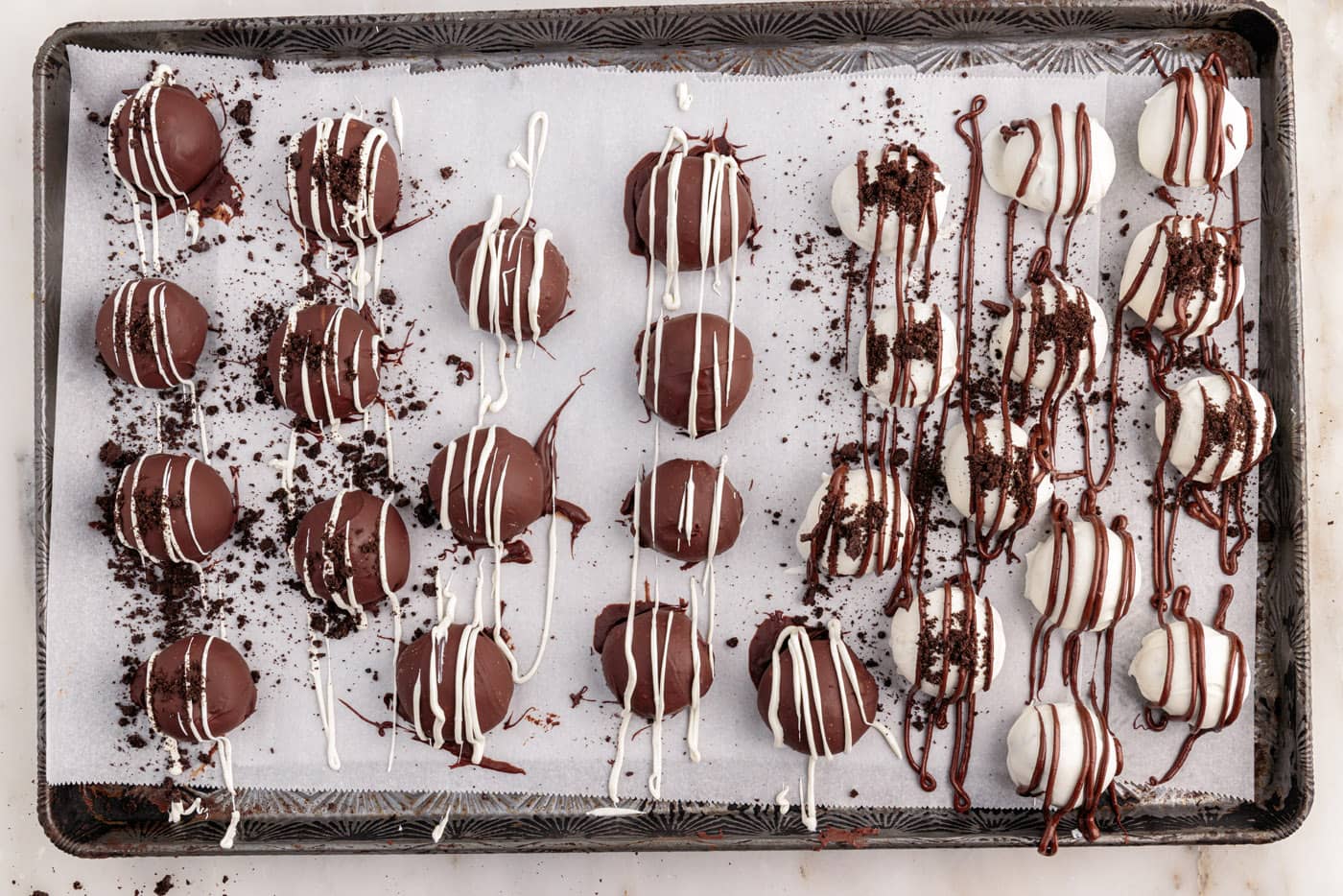 drizzled and decorated oreo truffles on a baking sheet