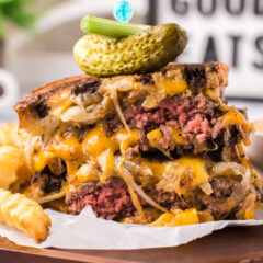 Patty Melt cut in half stacked on top of each other topped with a pickle