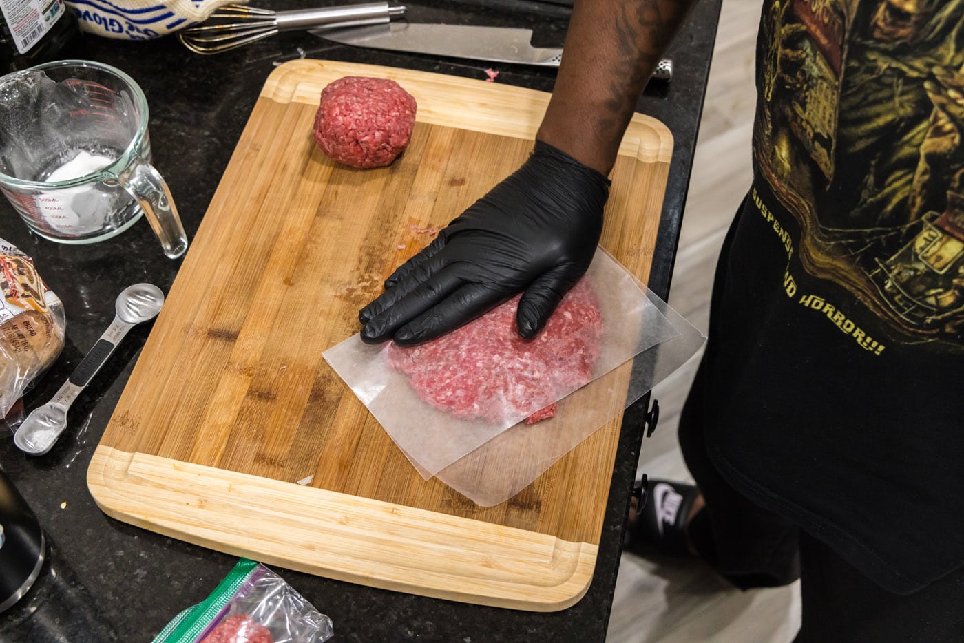 pressing down on parchment covered burger meat to flatten