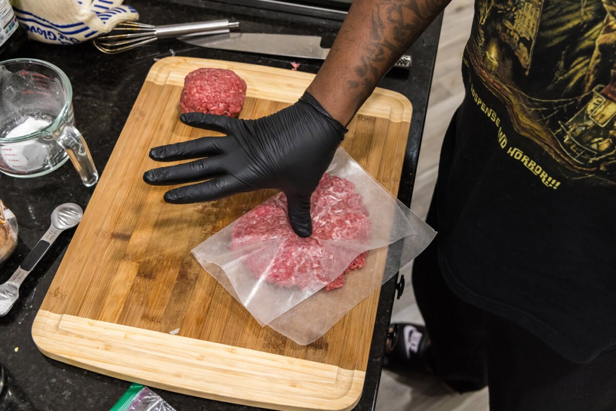 thumb pressing into burger patty to create an indent