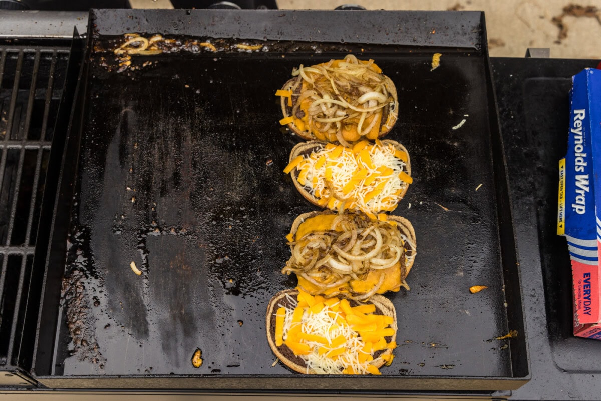onions on top of burger and rye bread on a grill