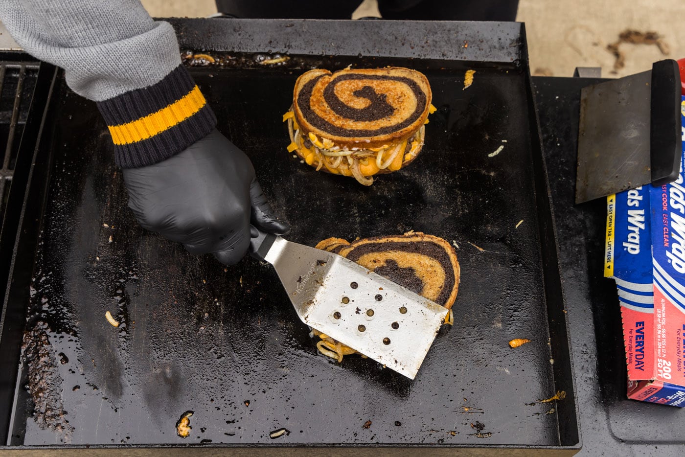 spatula pressing down on patty melt on a griddle