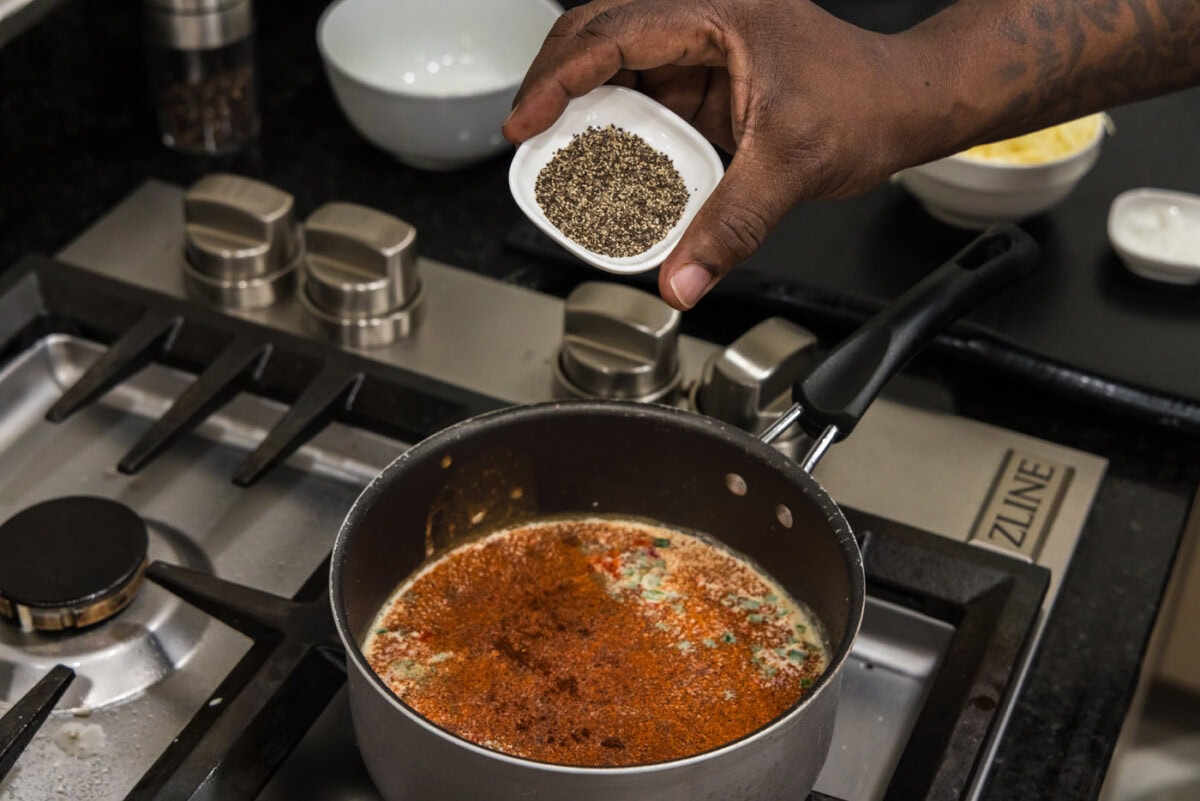 adding spices to queso dip in saucepan