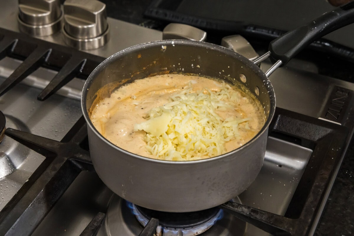 mozzarella and white cheddar added to saucepan with sauce mixture