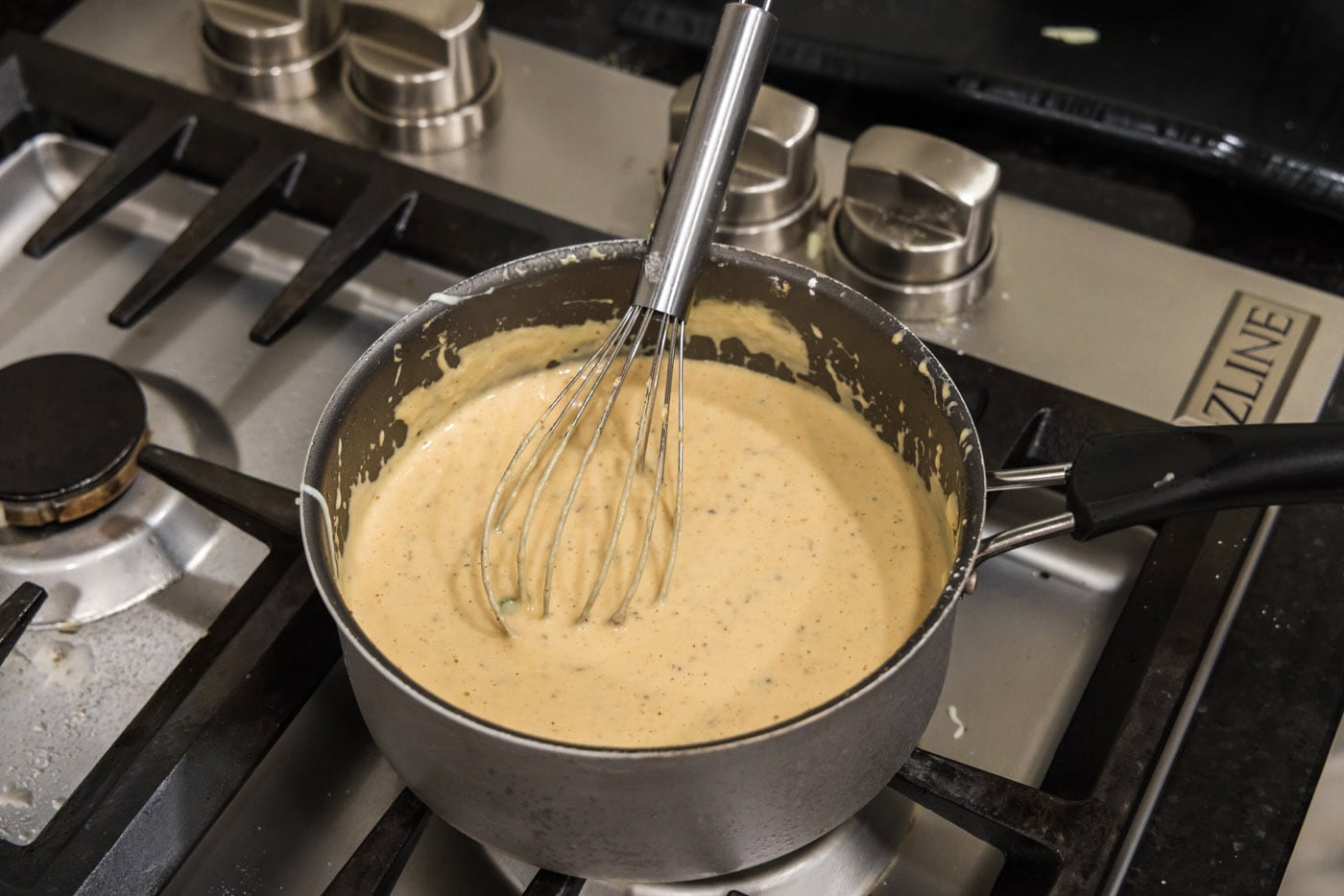 whisking queso dip in a saucepan