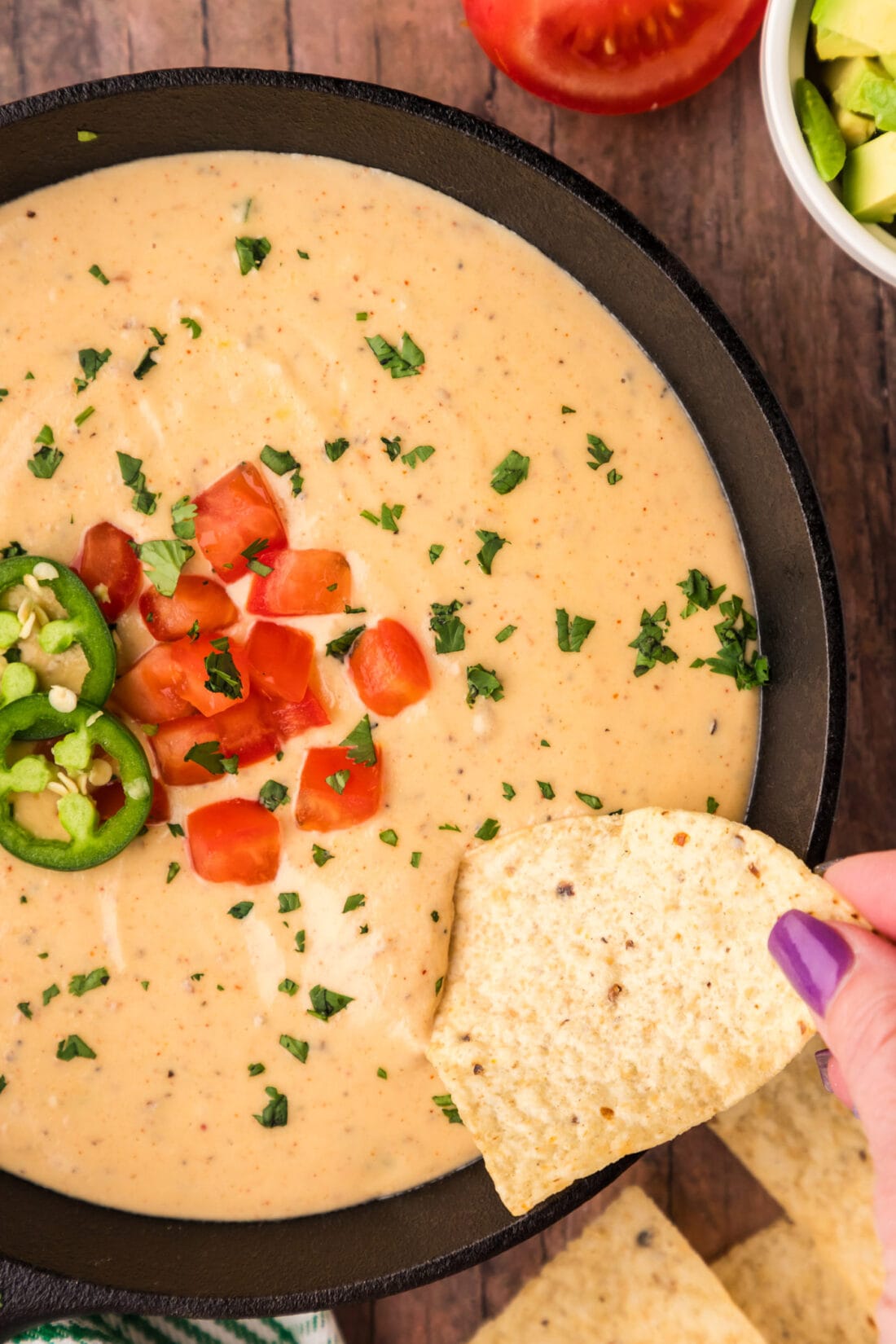 Tortilla chip being dipped into a skillet of Queso Dip