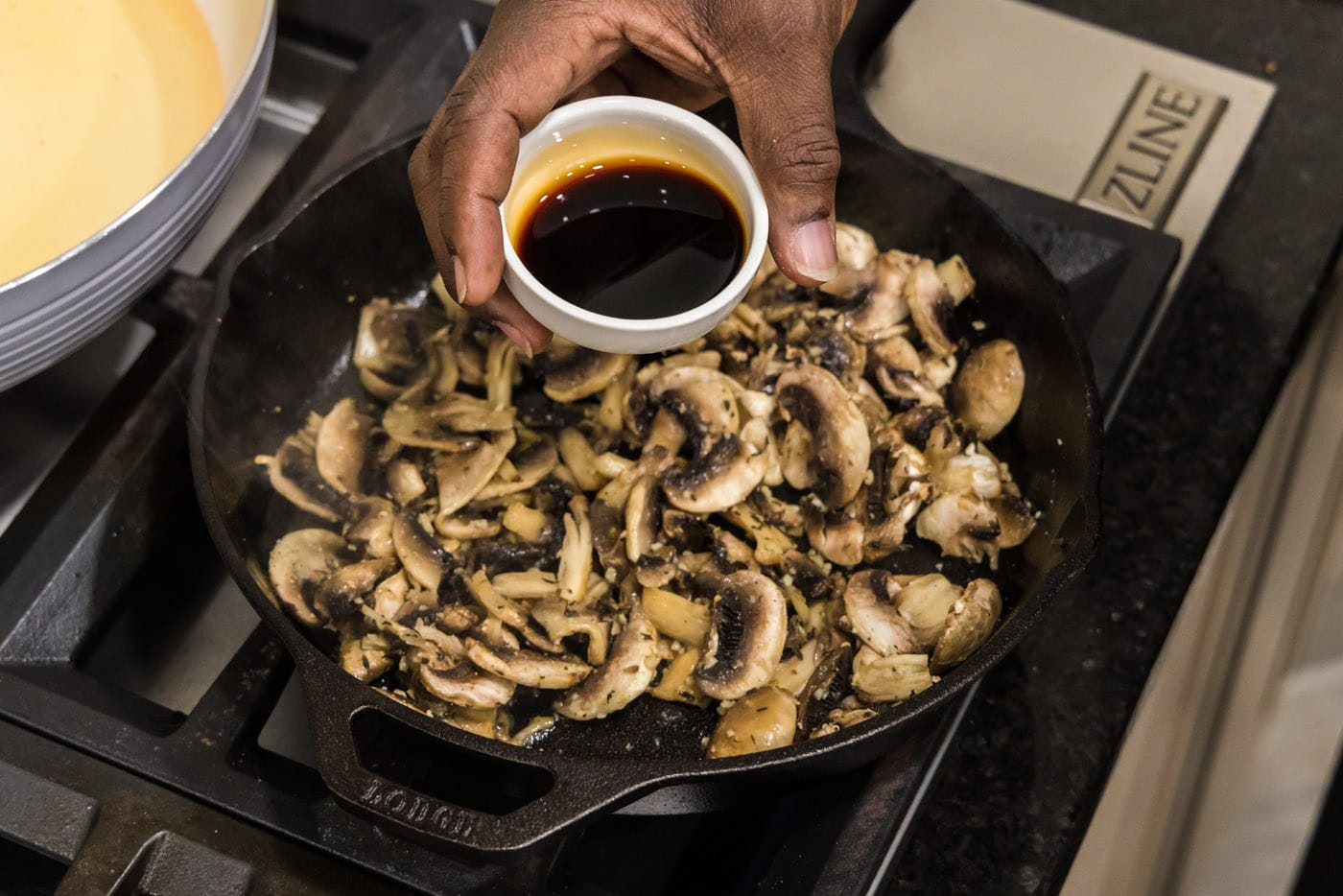 adding soy sauce to mushrooms and garlic in skillet