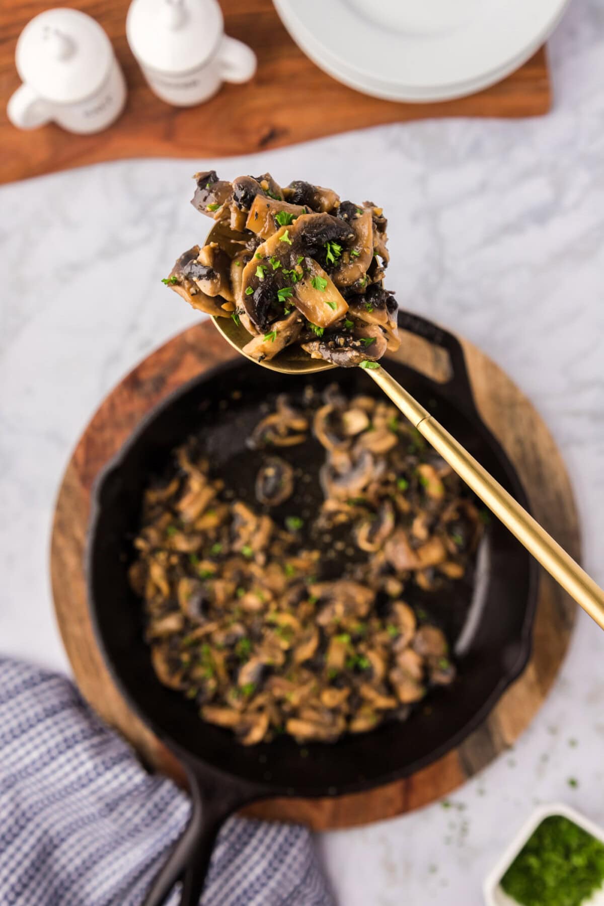 Spoonful of Sautéed Mushrooms held over a skillet