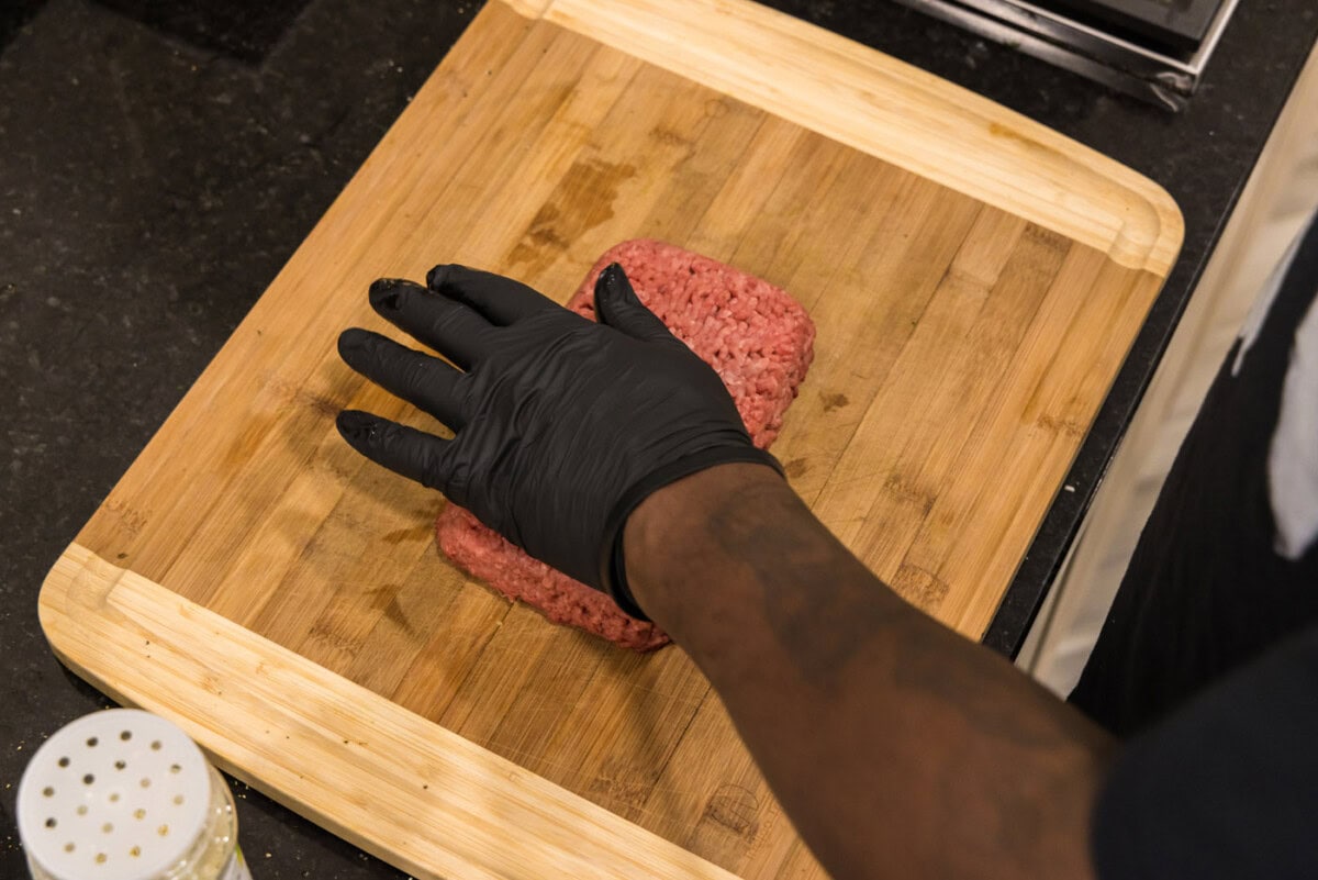 hand pressing down on ground beef