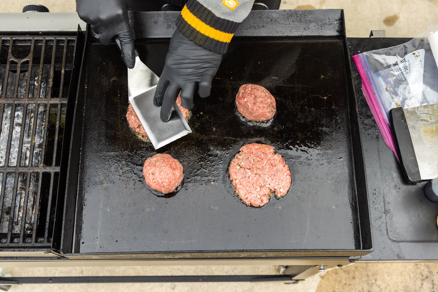 pressing down on burger patties on a griddle