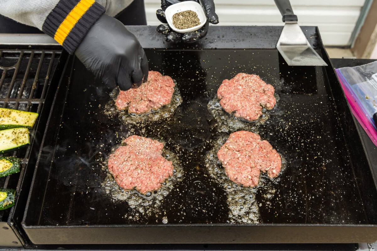 sprinkling seasonings on top of burger patties