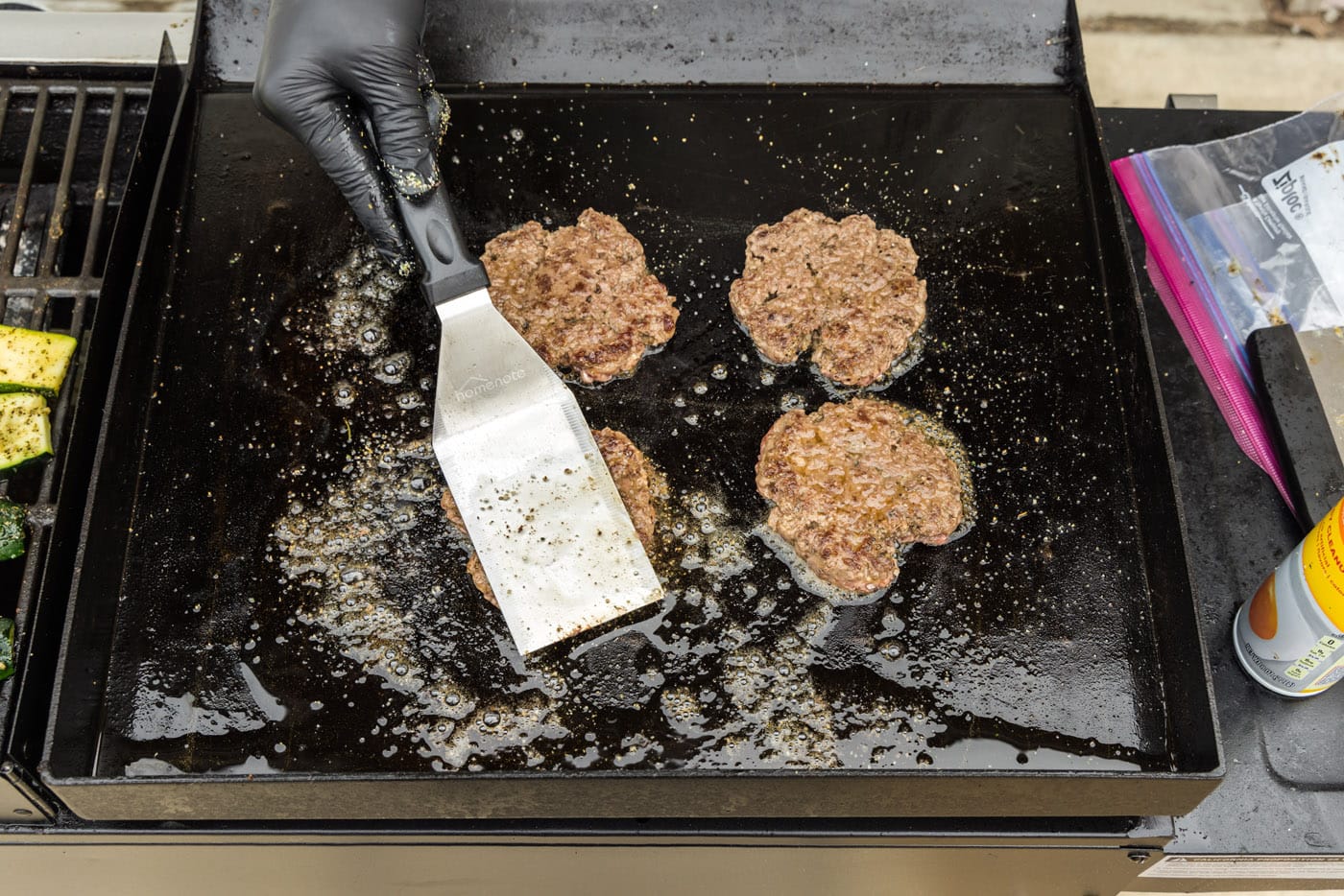 spatula flattening burger patties on a griddle