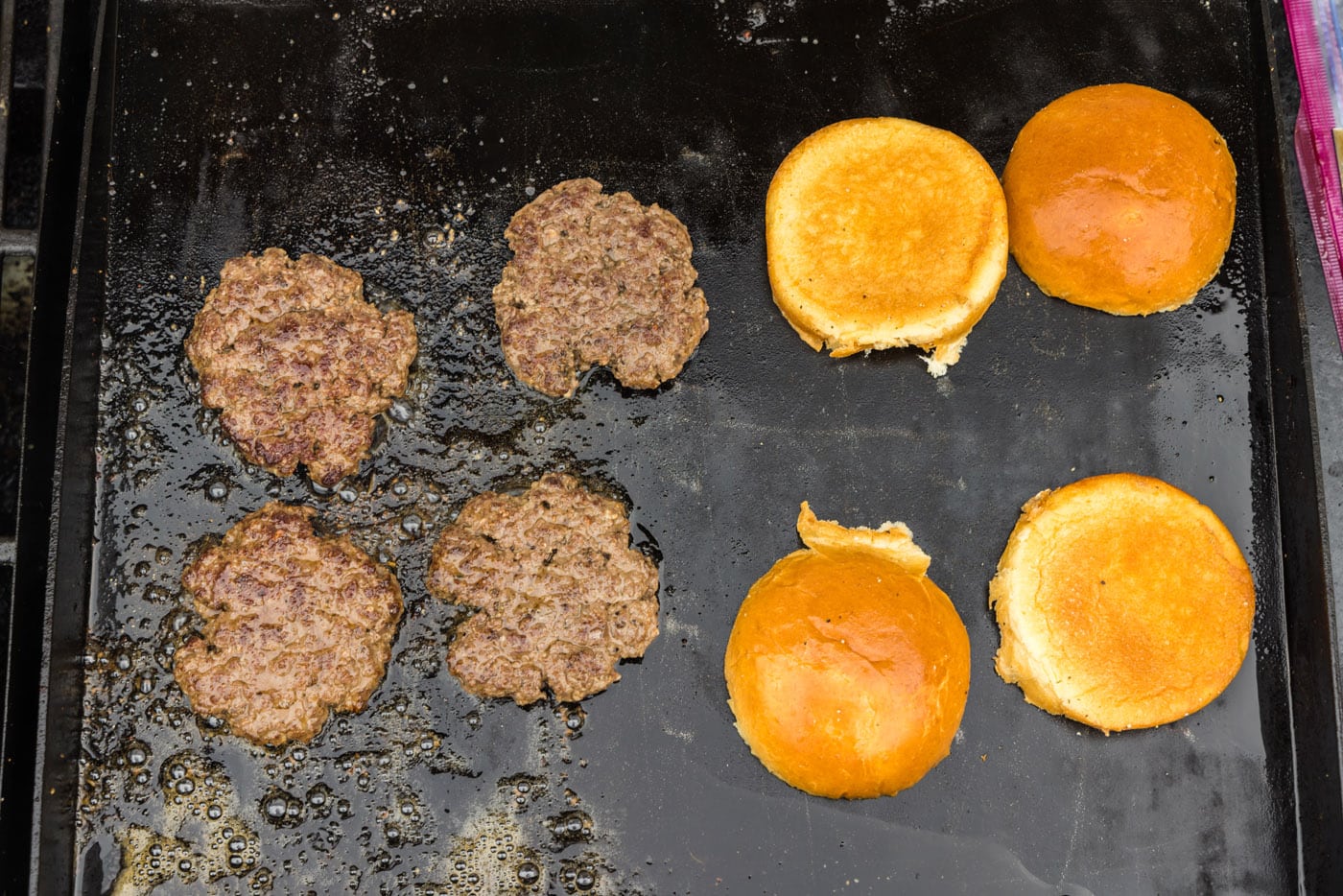 buns and burger patties on a griddle grate