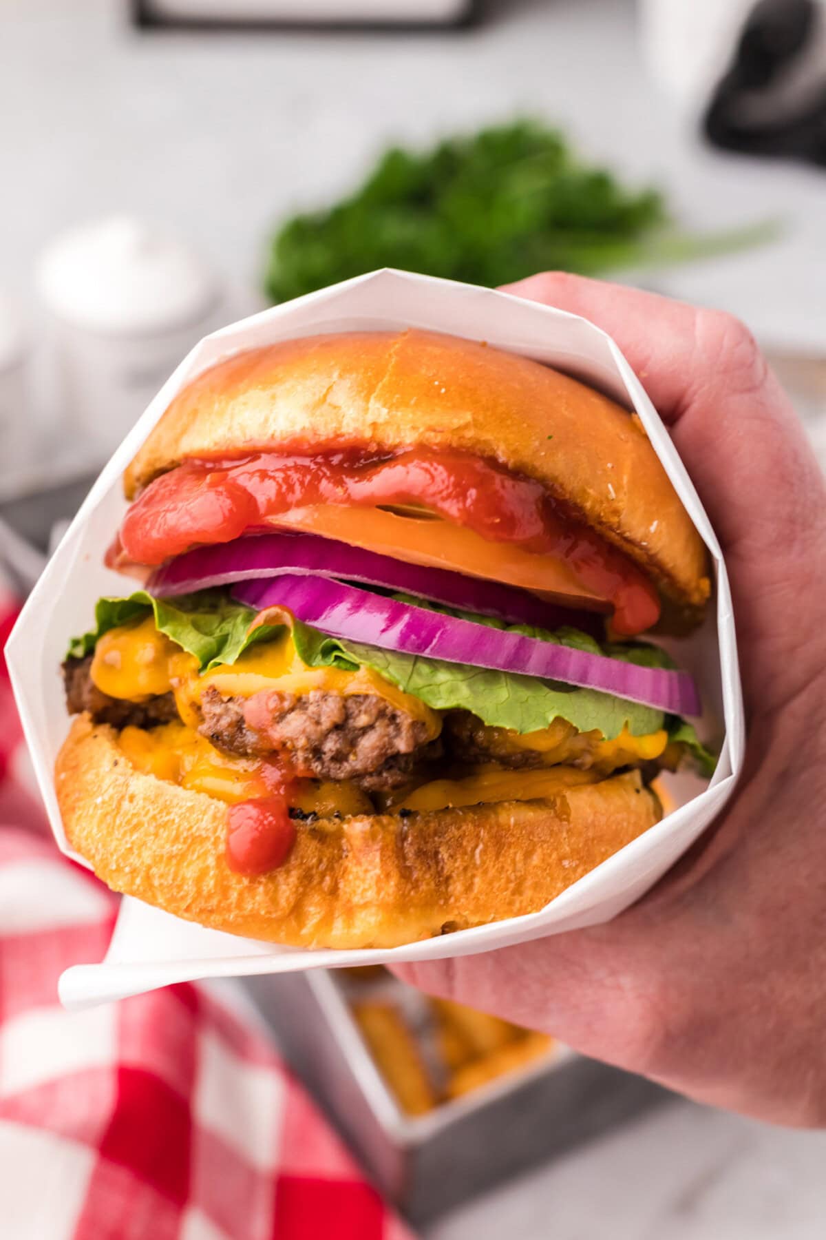 Hand holding a Smash Burger wrapped in parchment paper