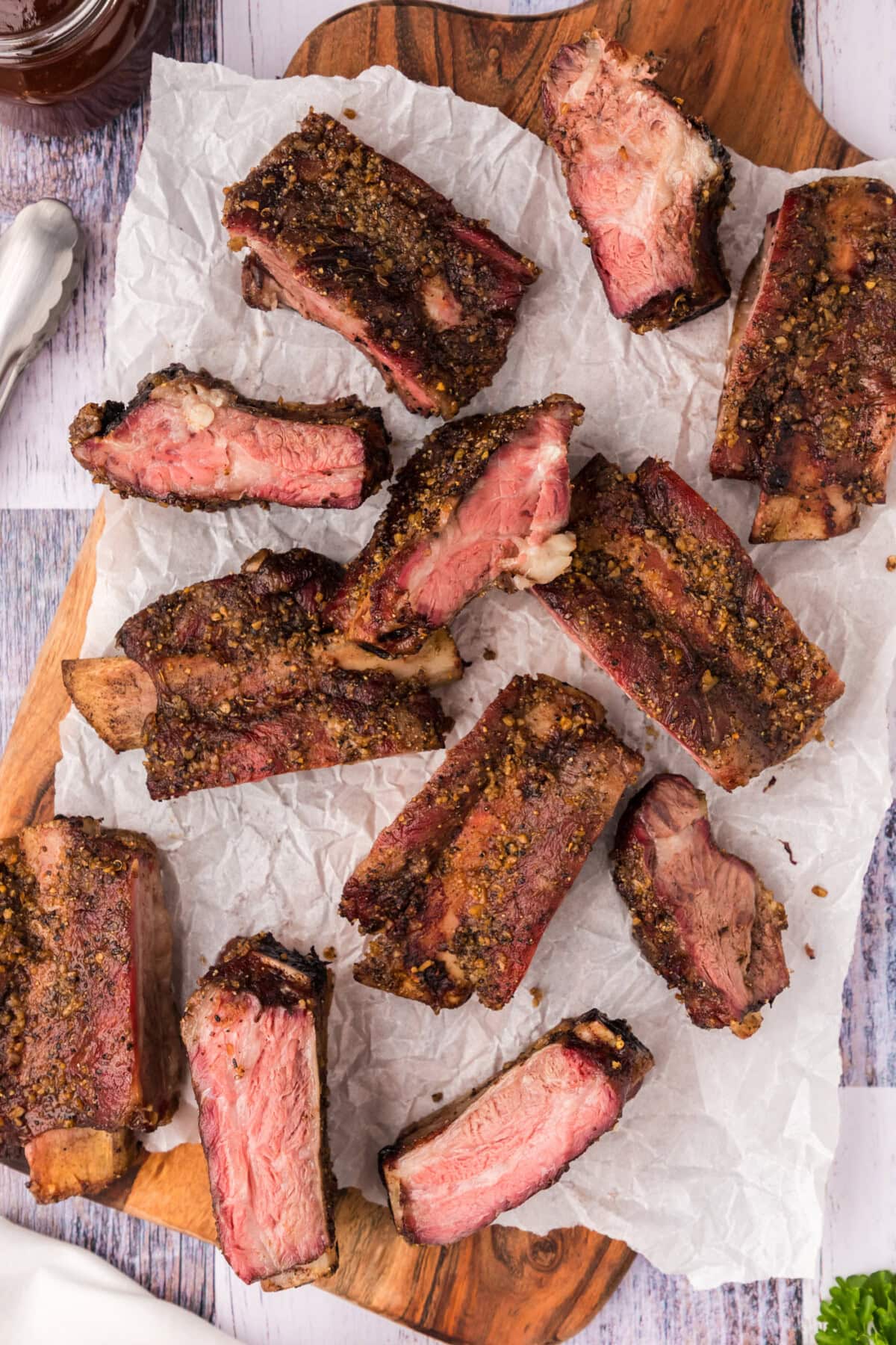 Smoked Beef Ribs resting on a wooden platter covered in parchment paper