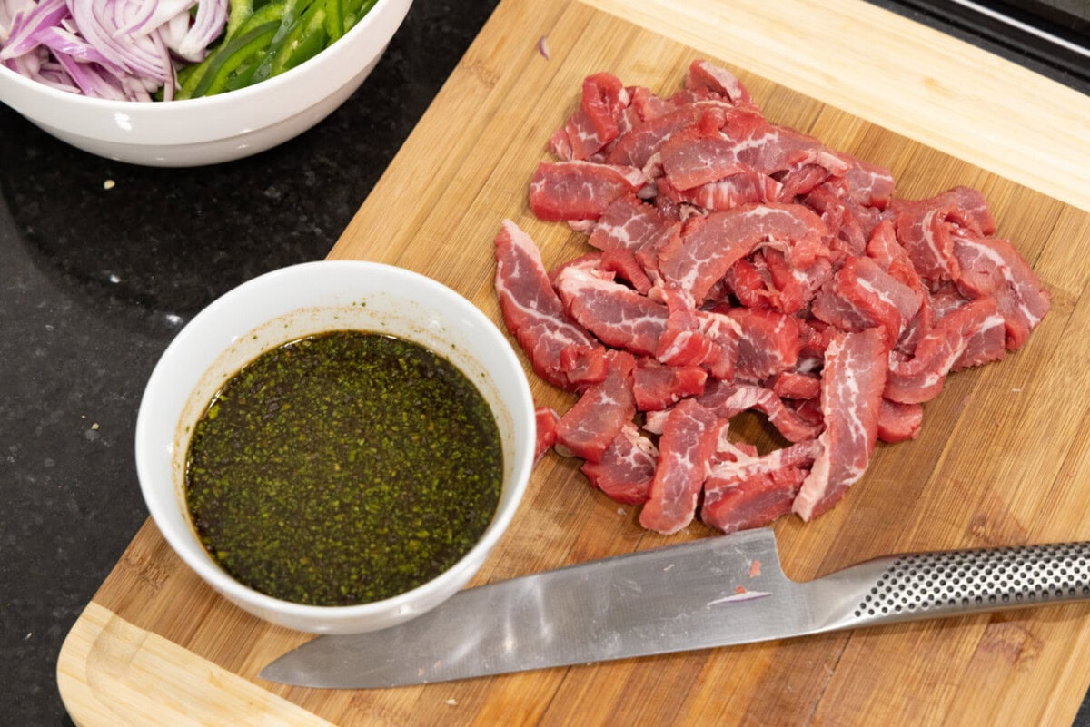sliced flank steak with marinade on the side