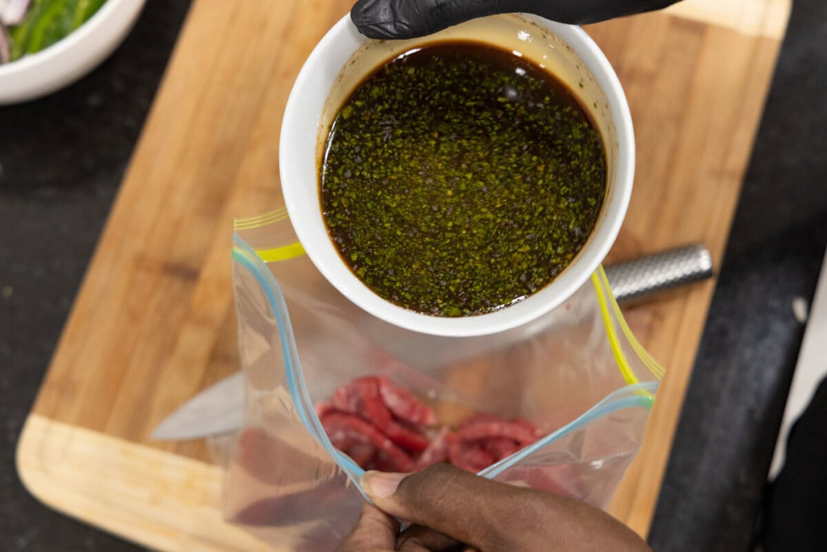 pouring steak marinade into bag with flank steak