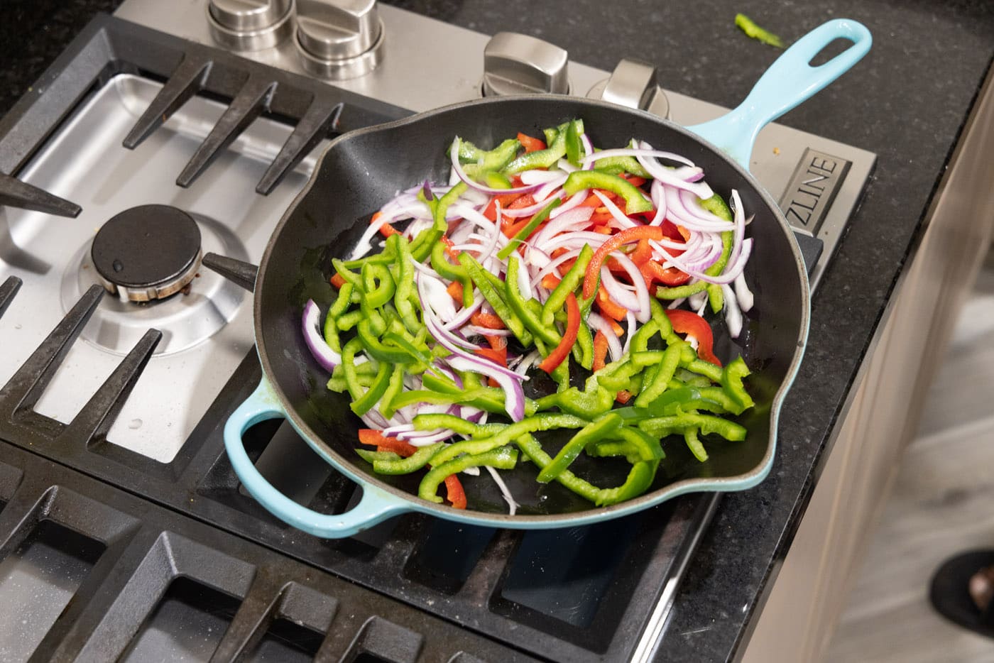 cooking bell peppers and onions in a skillet with oil