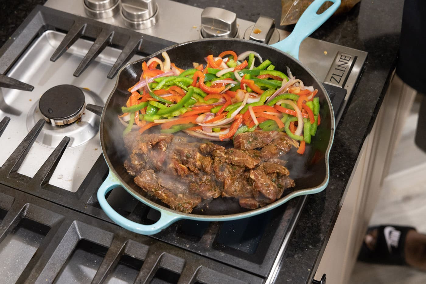 marinated beef strips added to pan with veggies for fajitas