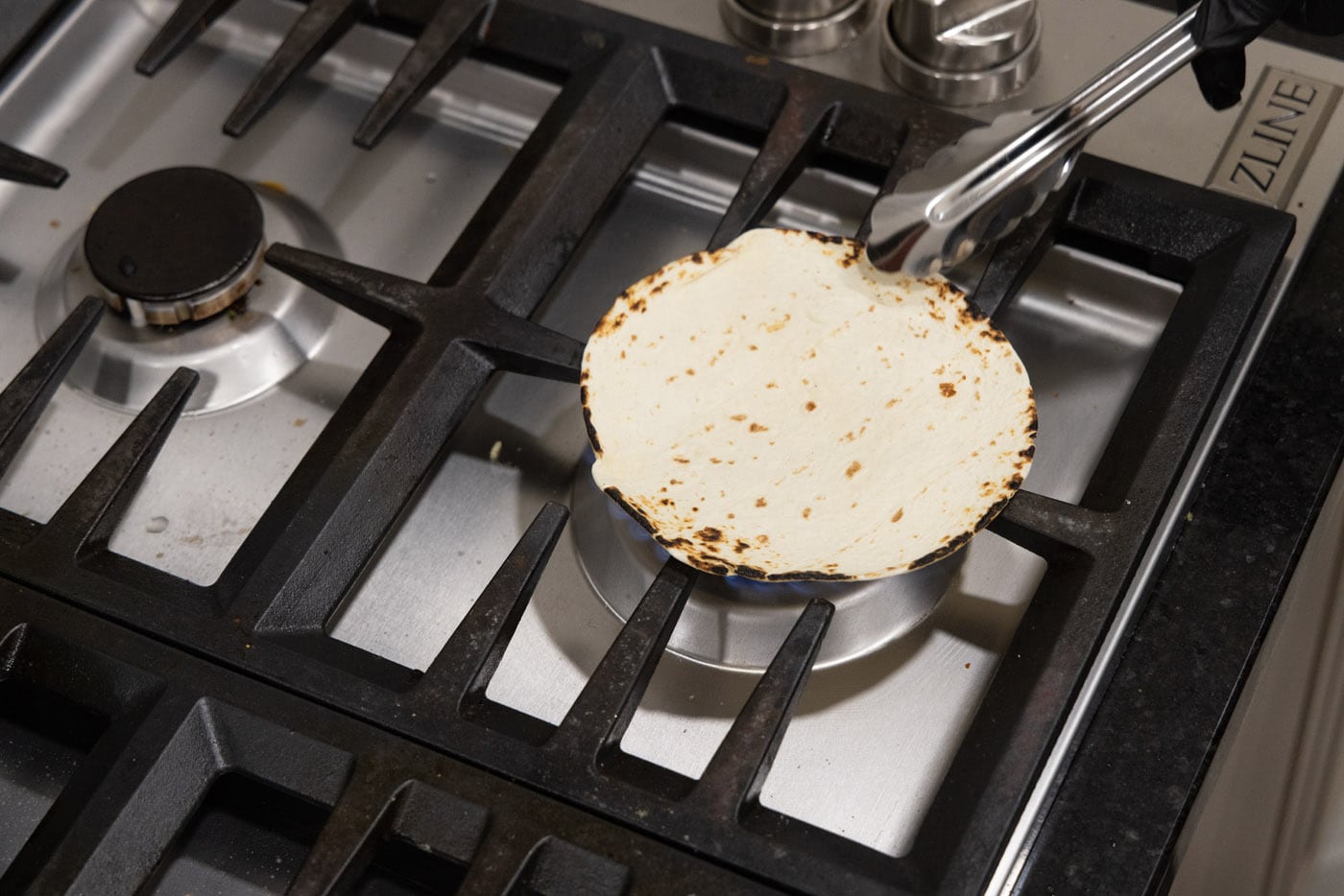charring corn tortillas over oven flame