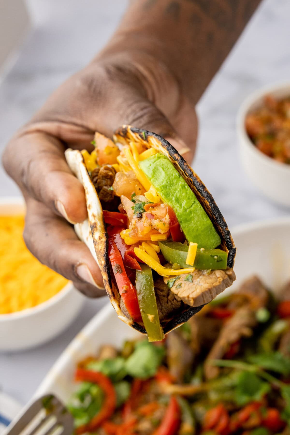 Hand holding Steak Fajitas wrapped in a tortilla 