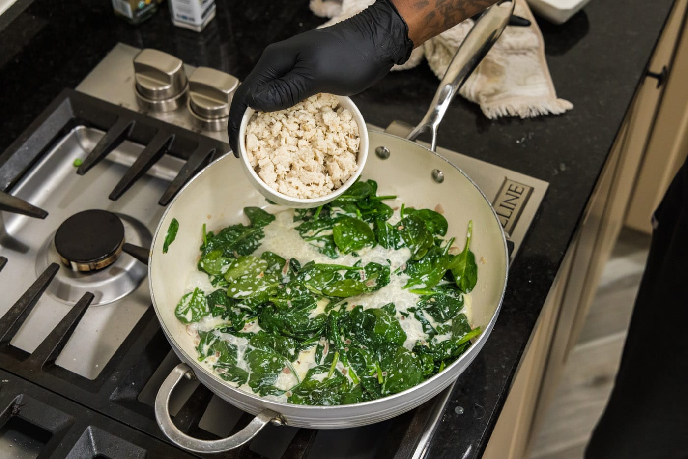 adding crab meat to skillet with spinach