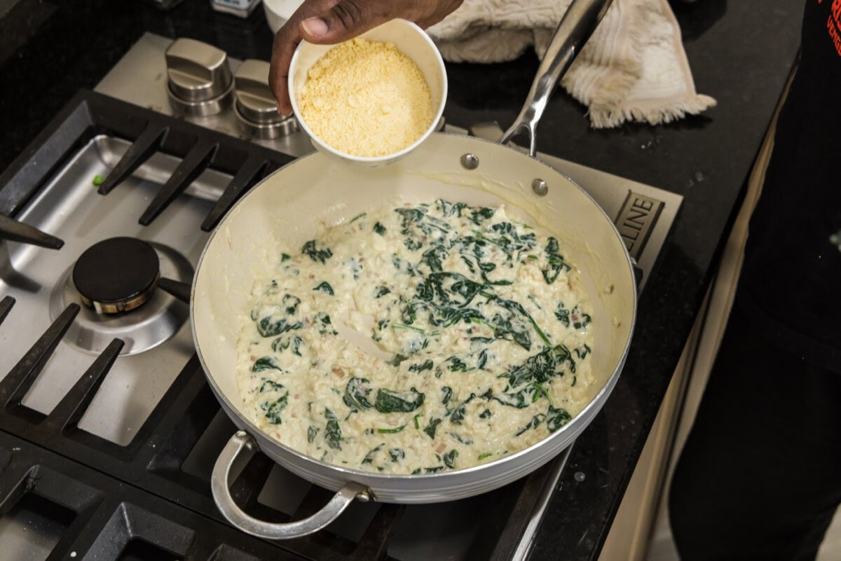 adding parmesan cheese to salmon stuffing in a skillet