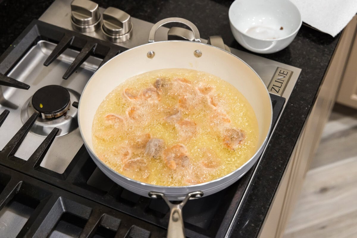 deep frying shrimp in a skillet of oil