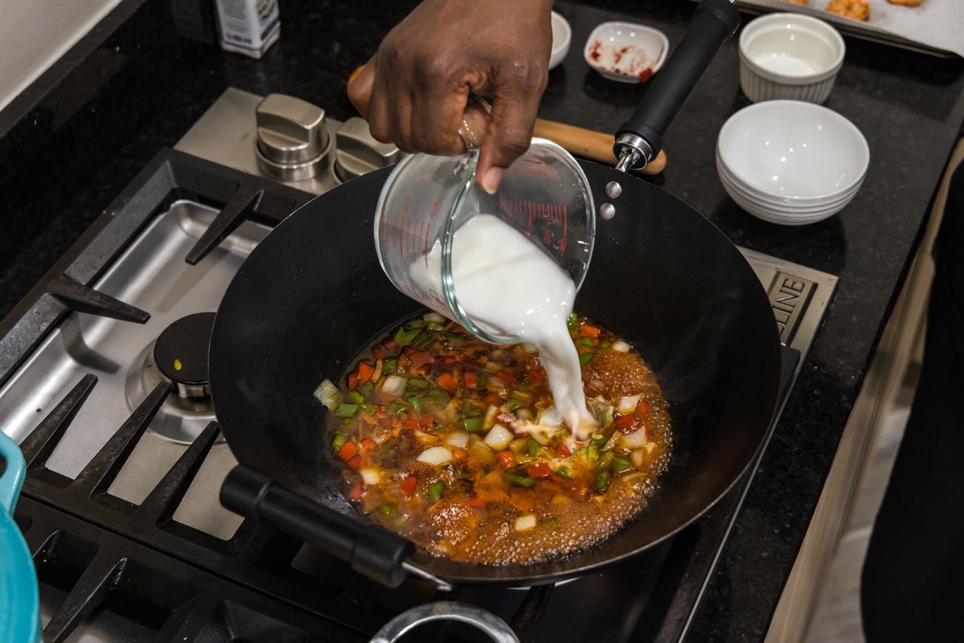 pouring cornstarch slurry into sweet and sour sauce in a skillet with vegetables