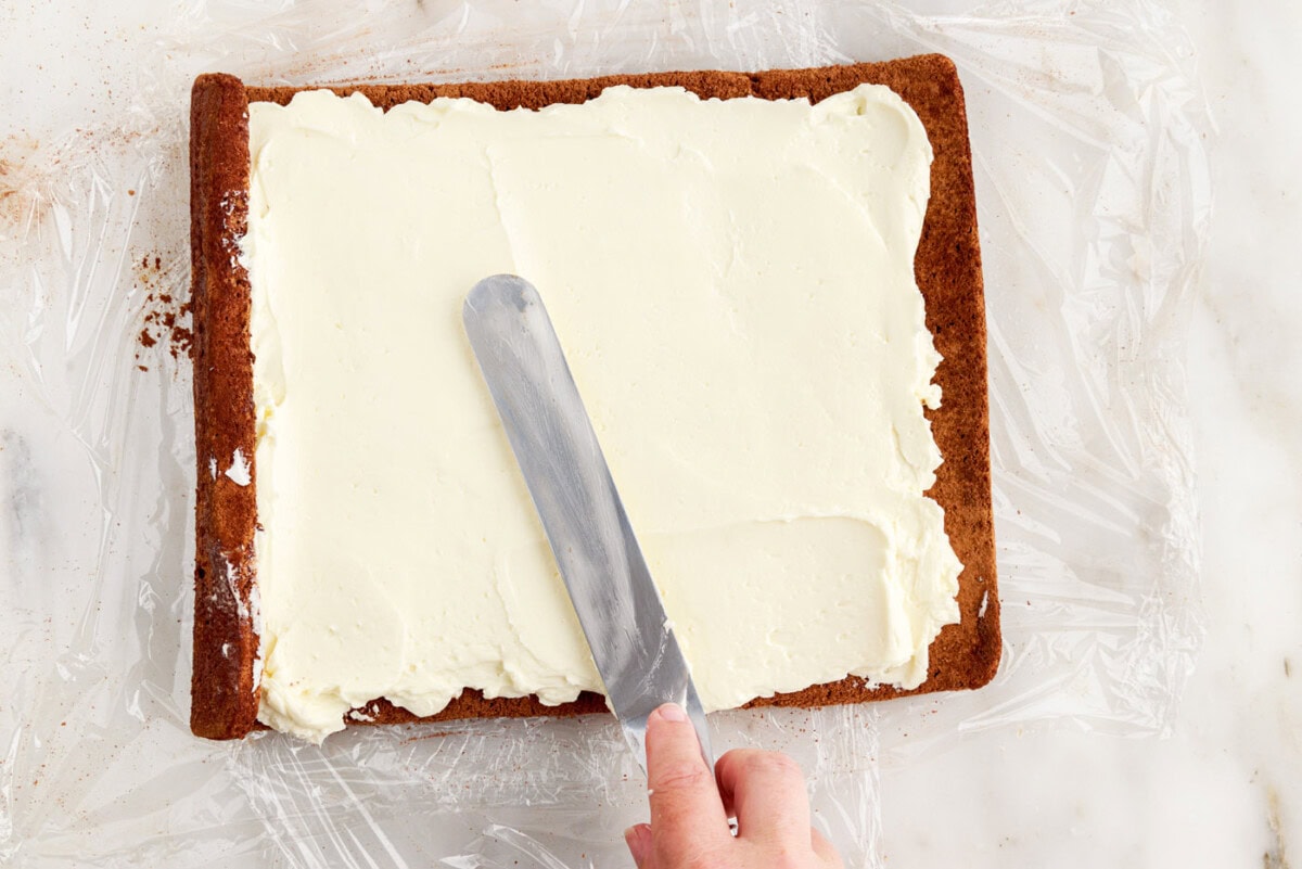 spreading frosting over log cake