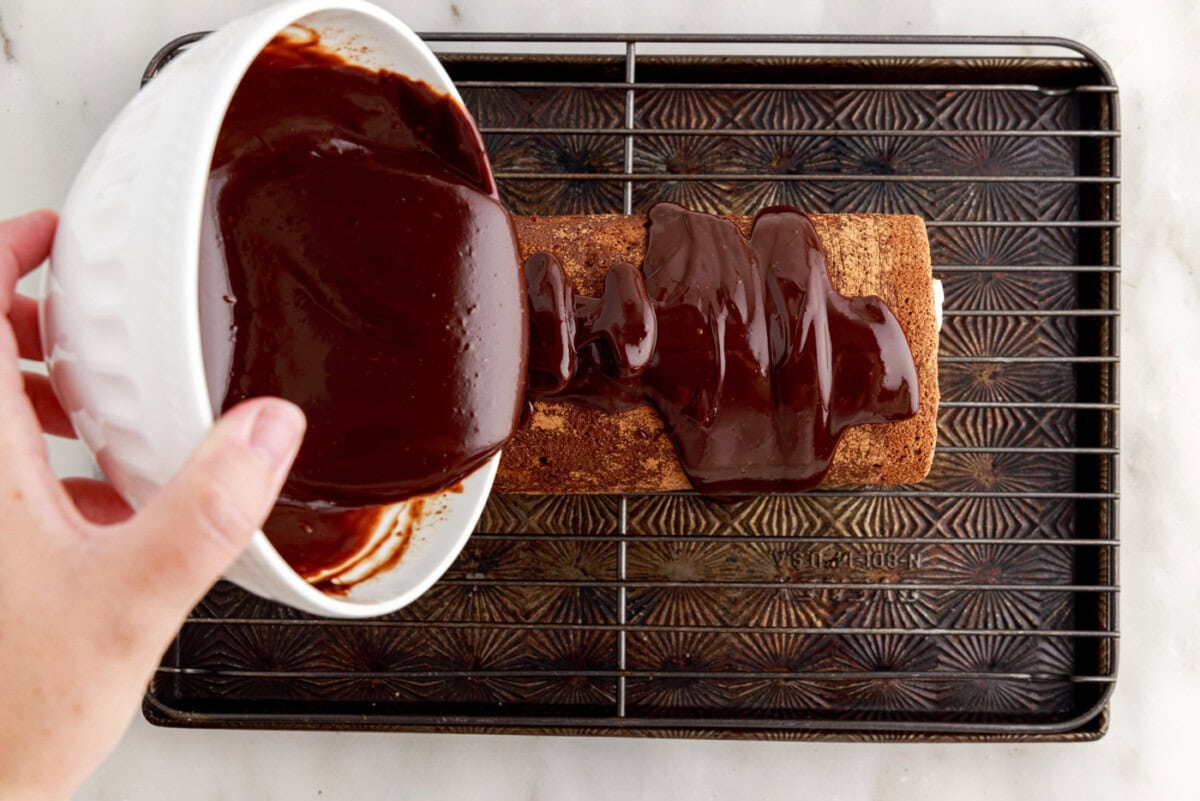 pouring chocolate ganache on top of swiss roll