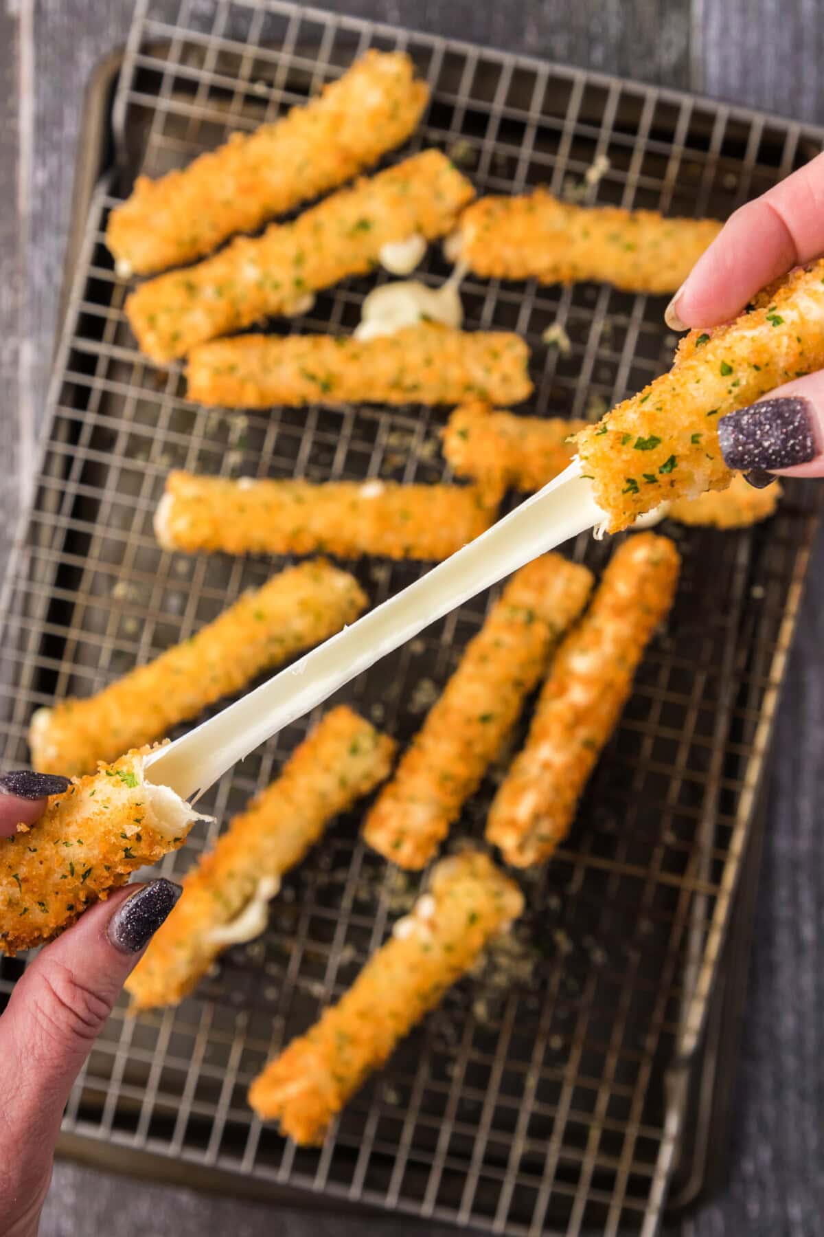 Wonton Cheese Stick cheese pull over a pan of Wonton Cheese Sticks