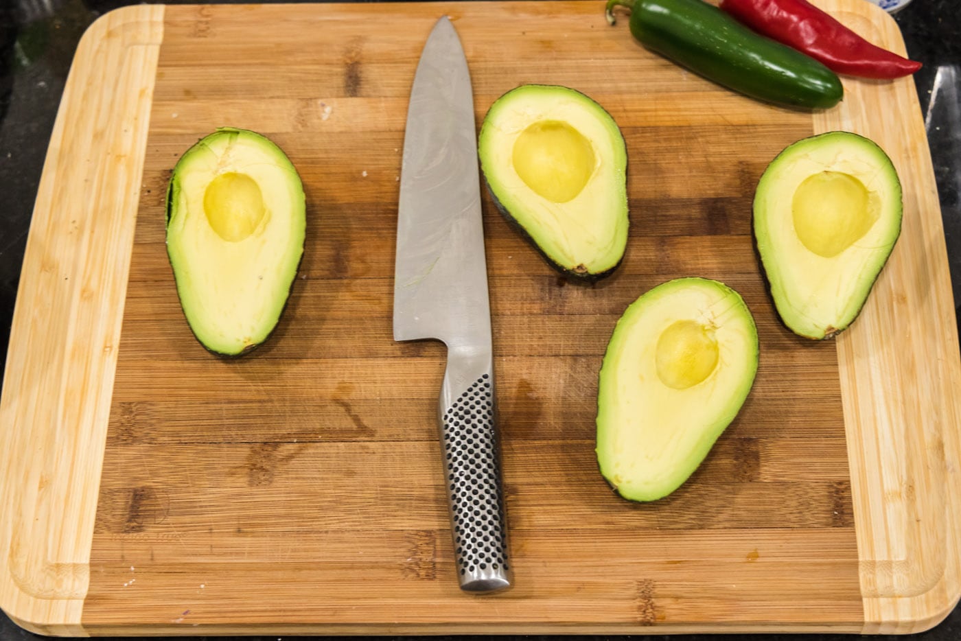 knife on a cutting board with sliced avocados
