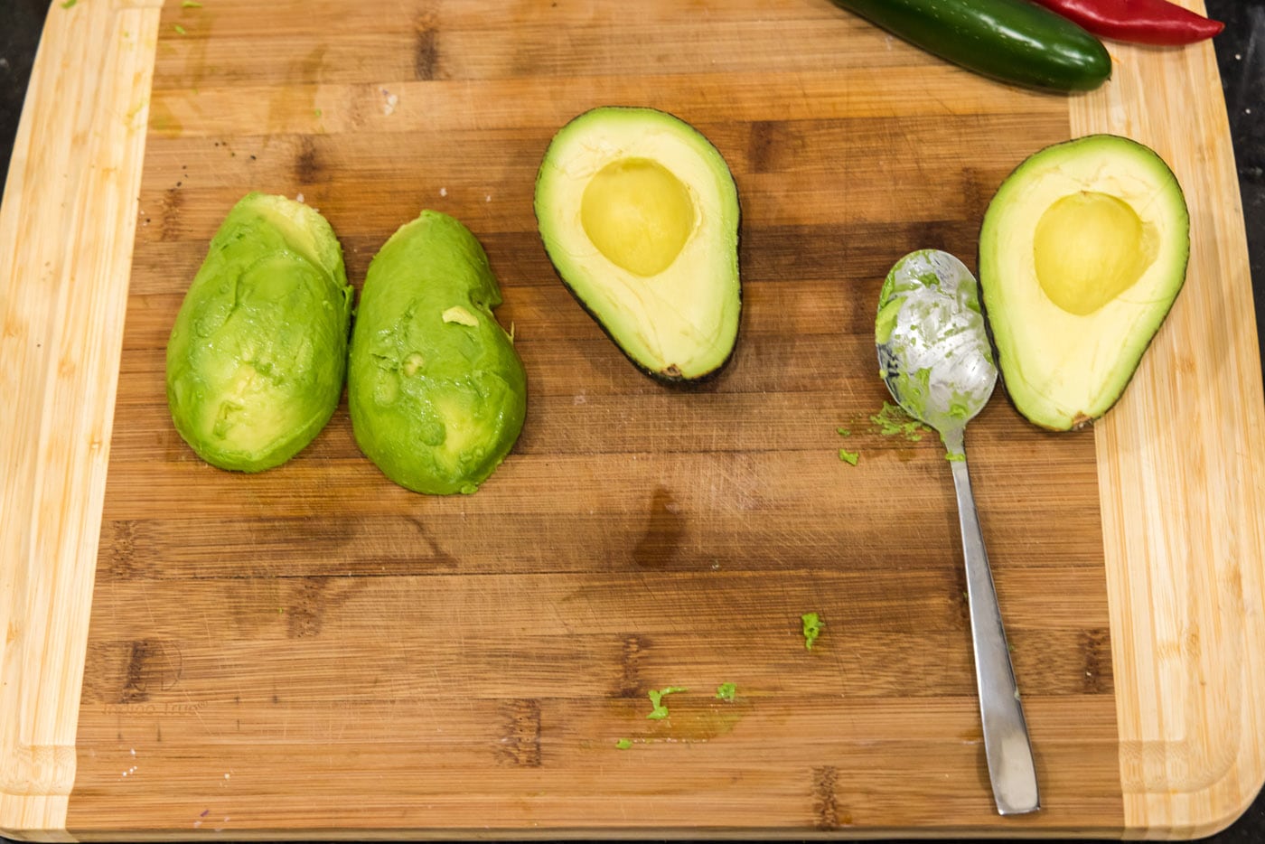 skinning avocados on a cutting board with a spoon