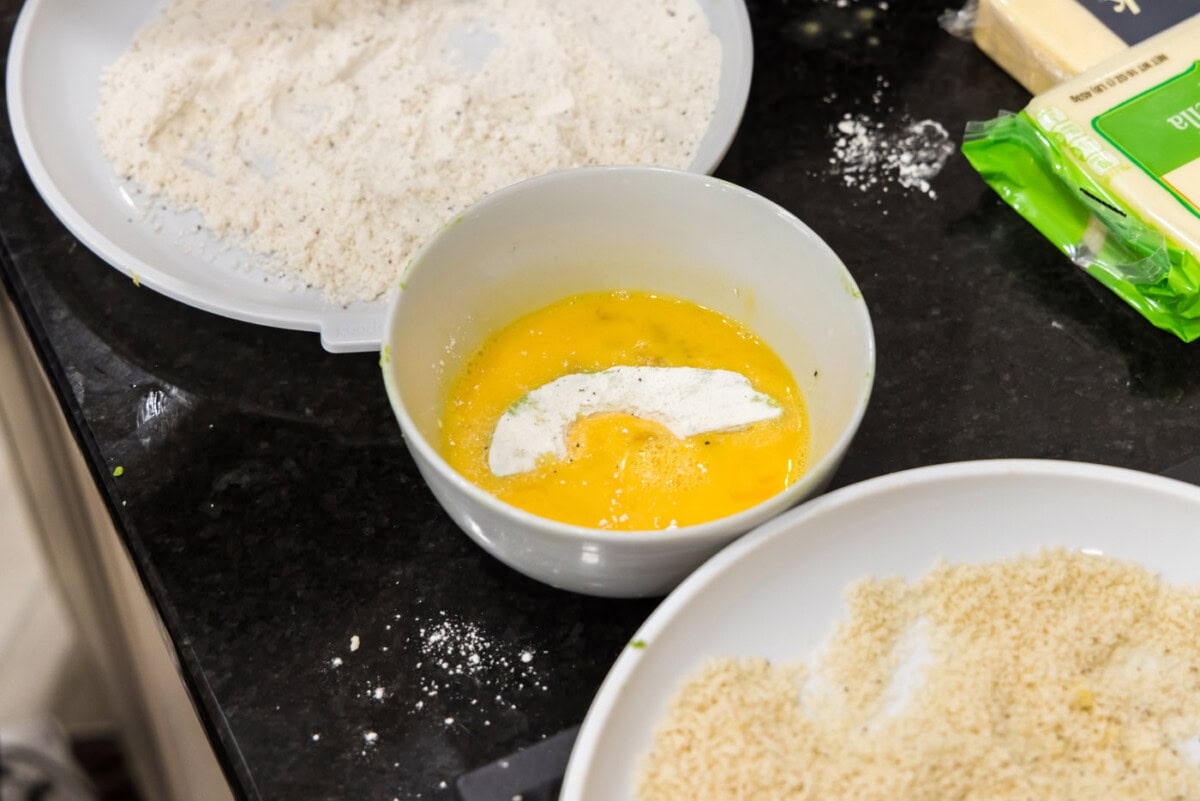 dipping floured avocado slice in egg