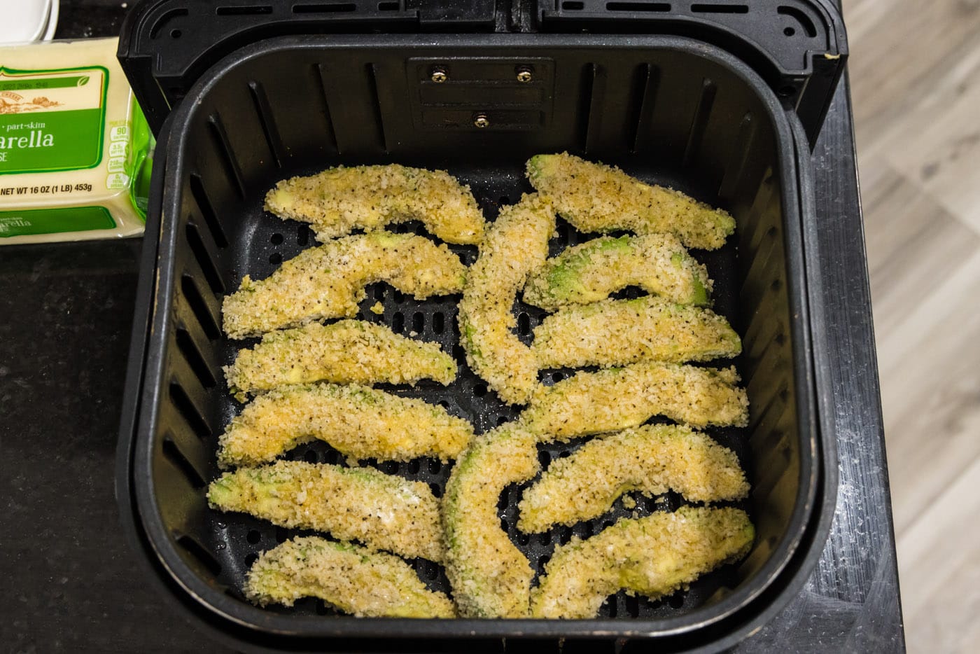 panko coated avocado fries in an air fryer basket