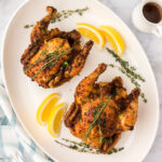 Air Fryer Cornish Hens on a platter with lemon wedges