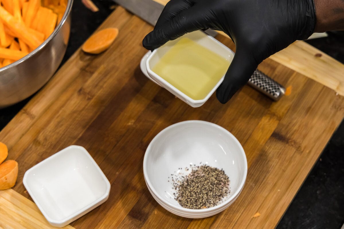 adding olive oil to pepper and salt in a bowl