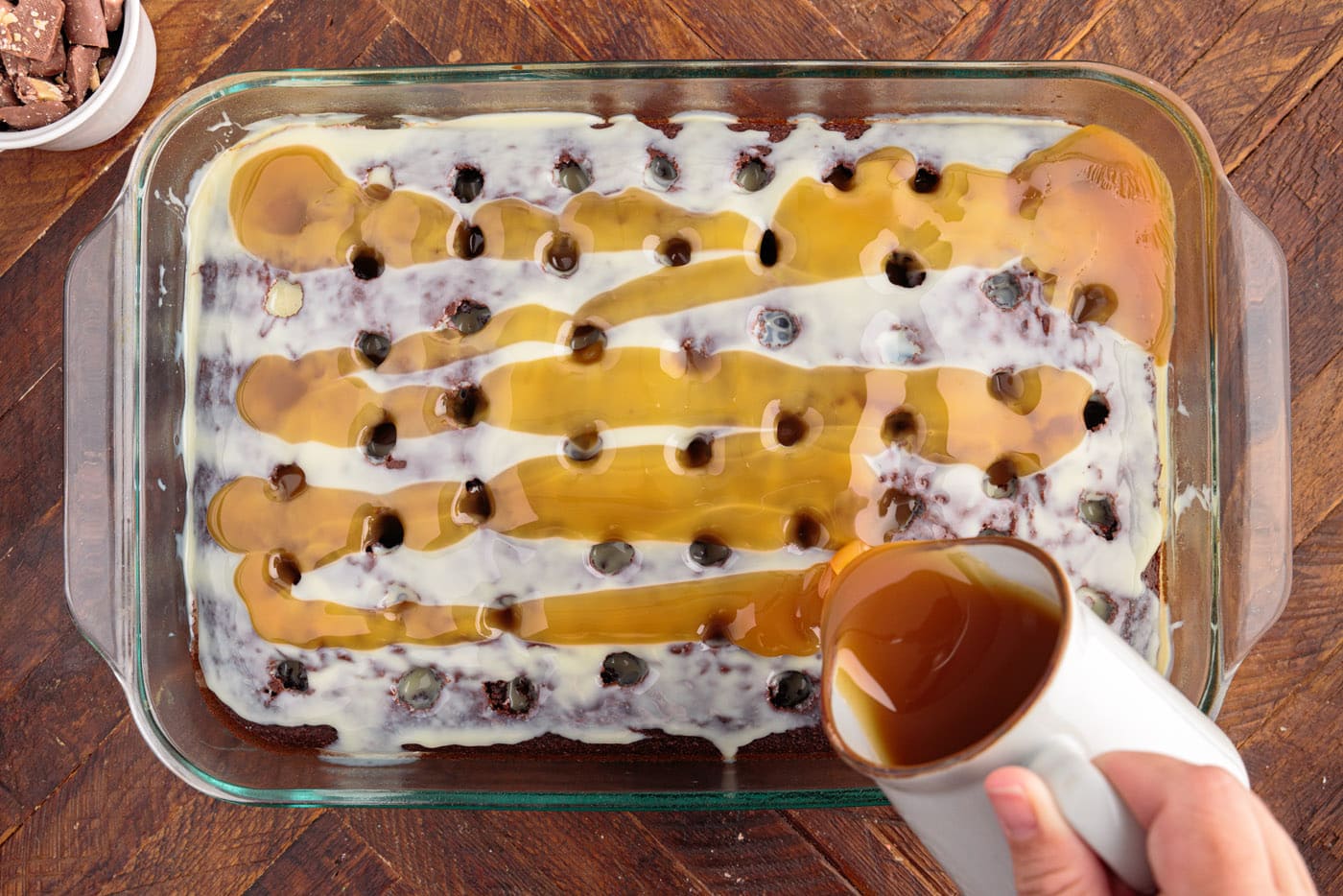 pouring caramel sauce over sweetened condensed milk on top of poke cake