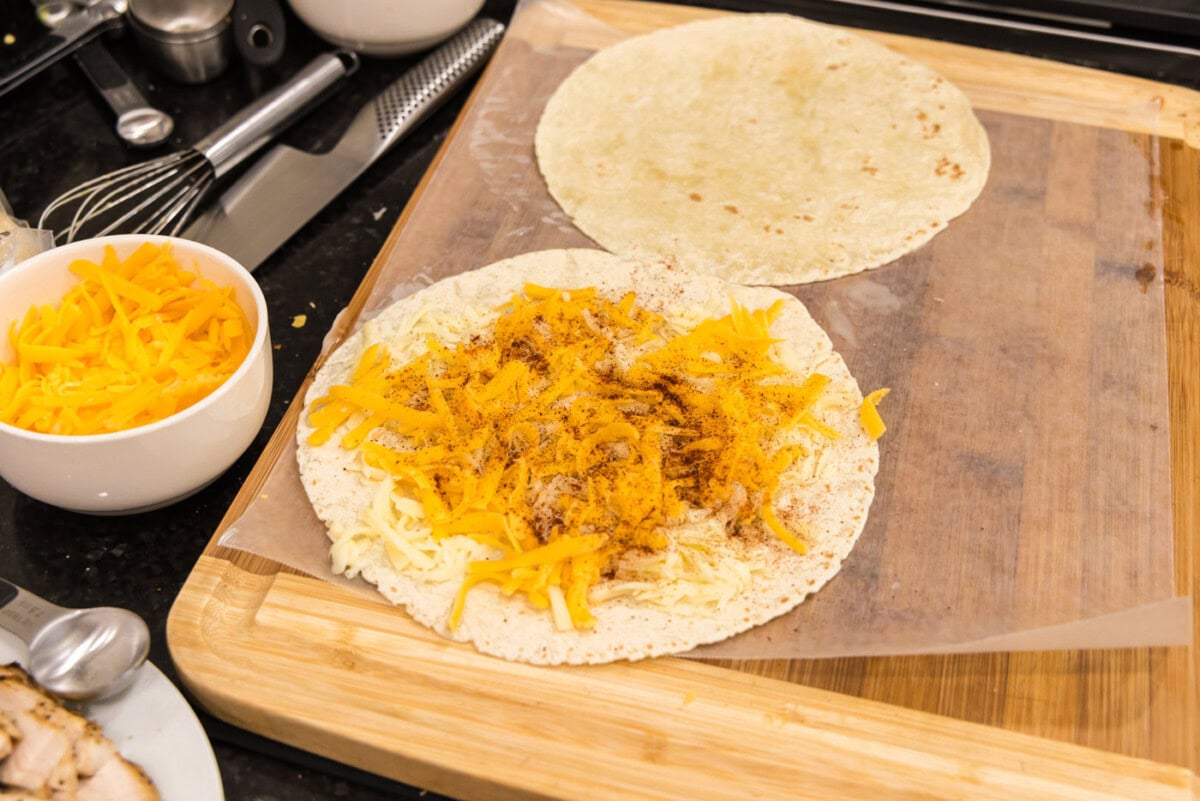 chili powder sprinkled over cheese on tortilla