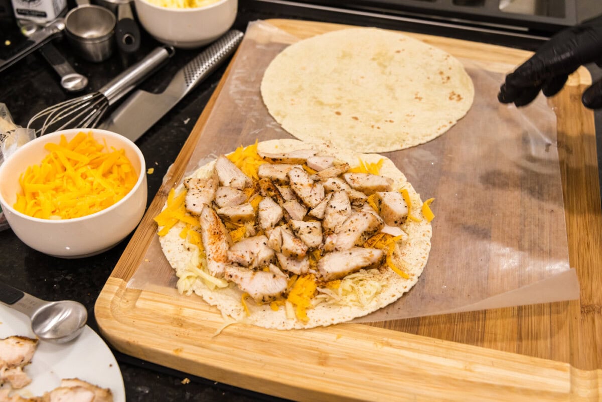 sliced chicken breast over shredded cheese on a tortilla