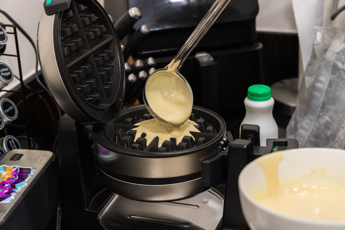 ladle pouring waffle batter into waffle iron