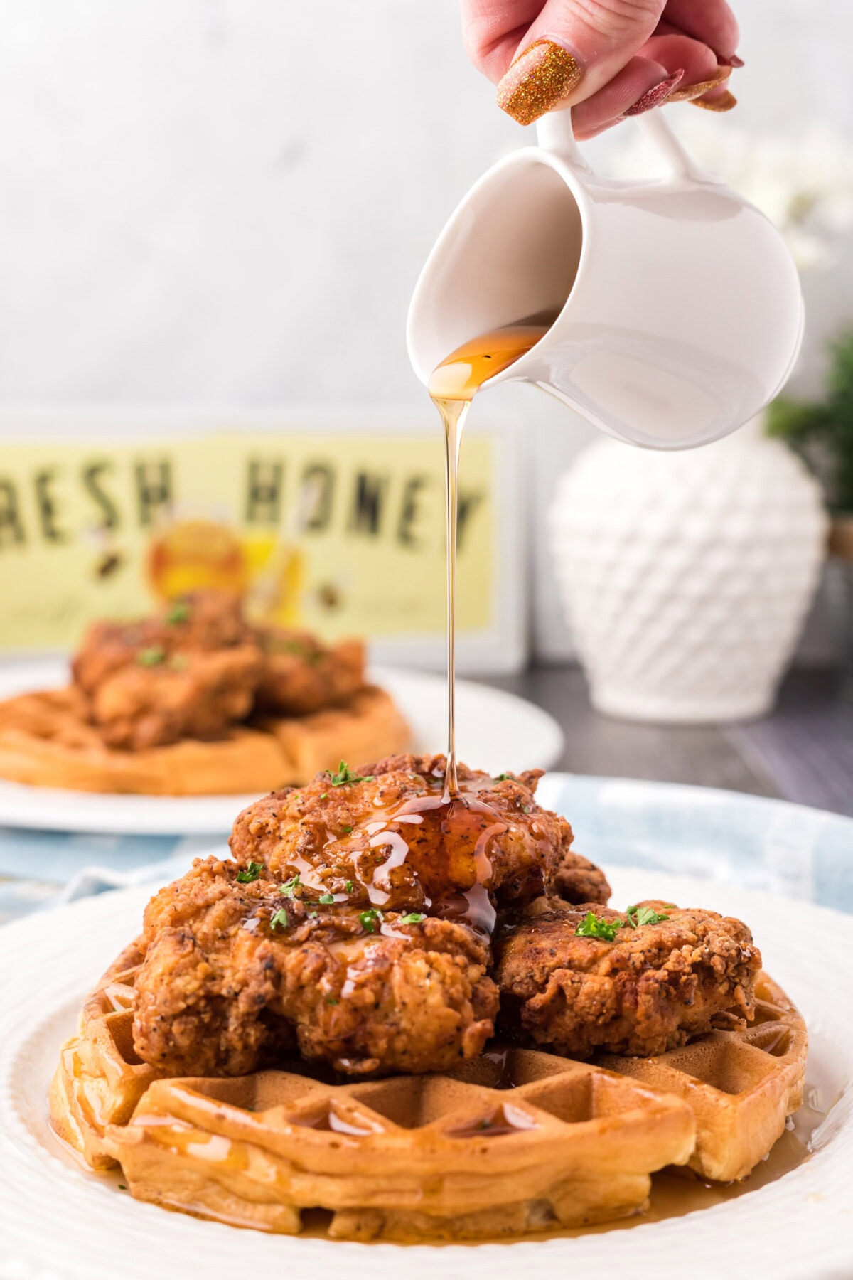 Syrup being drizzled over a plate of Chicken and Waffles
