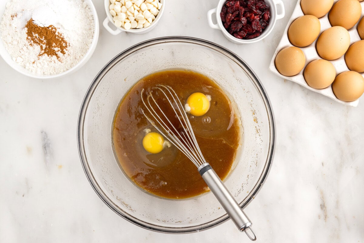 adding eggs to butter and sugar mixture in a bowl