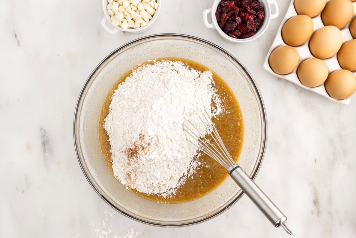 whisking flour into butter and sugar mixture in a bowl